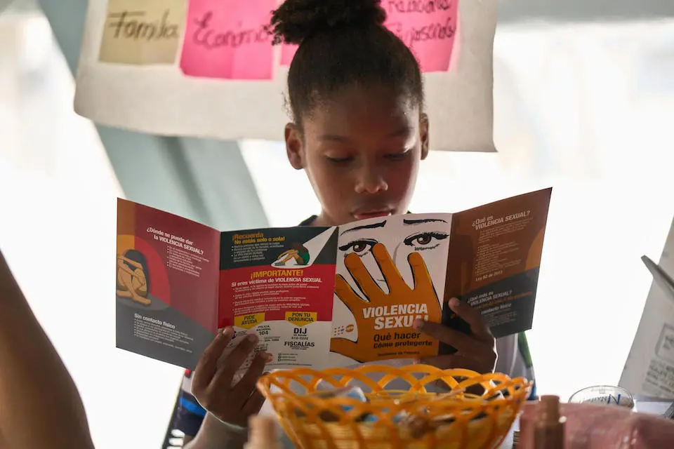 A girl reads a pamphlet about sexual violence and abuse inside the Self-Care Space at the Temporary Migration Reception Station in Lajas Blancas, Darien, Panama.