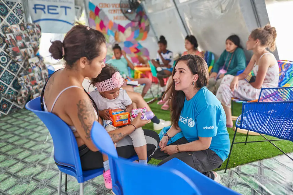 Johanna Tejada, Gender-based Violence and Protection Against Sexual Exploitation and Abuse Specialist with UNICEF Panama, right, speaks with a migrant mother and her child in a Self-Care Space in Lajas Blancas, Darien, Panama.