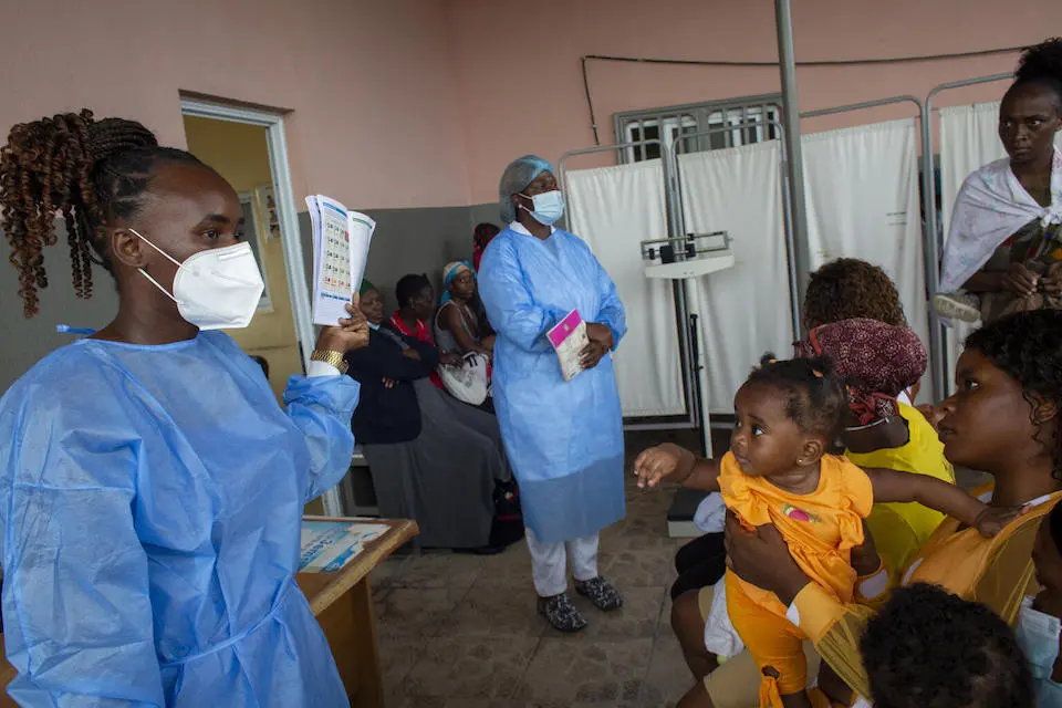 In Luanda, Angola, parents and caregivers wait for their children to receive routine immunizations, while listening to nurse Quénia Pinto, left, explain how children’s vaccination schedules work.