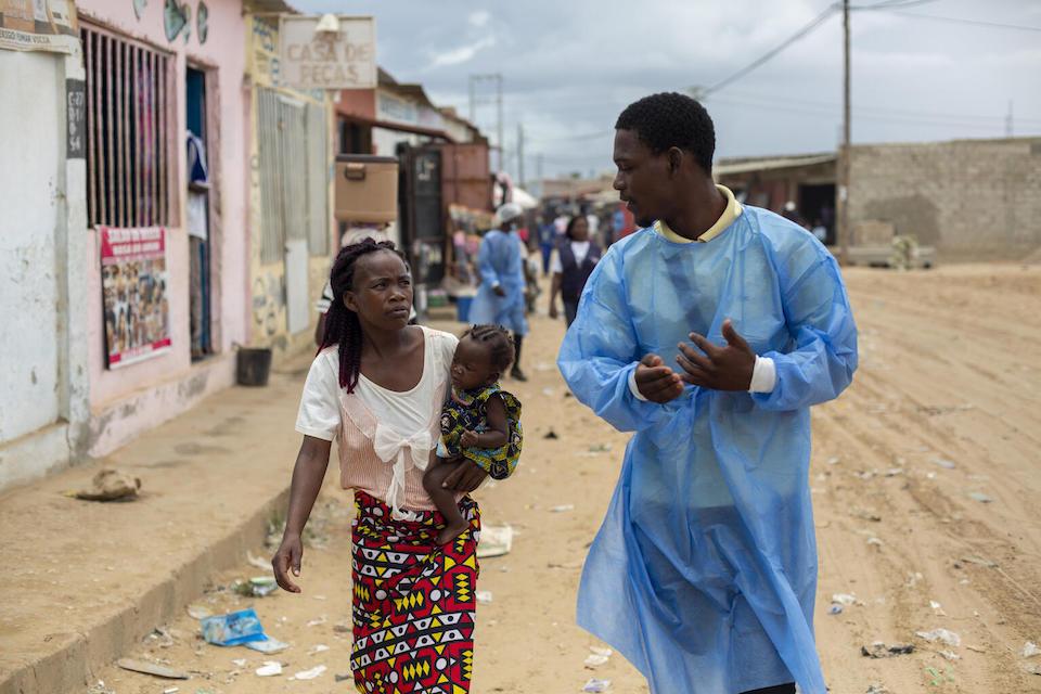 Health worker Nelson Franco Domingos walks with lorida Manuel, as she brings her 5-month-old daughter to be immunized at a mobile vaccination post in Angola.