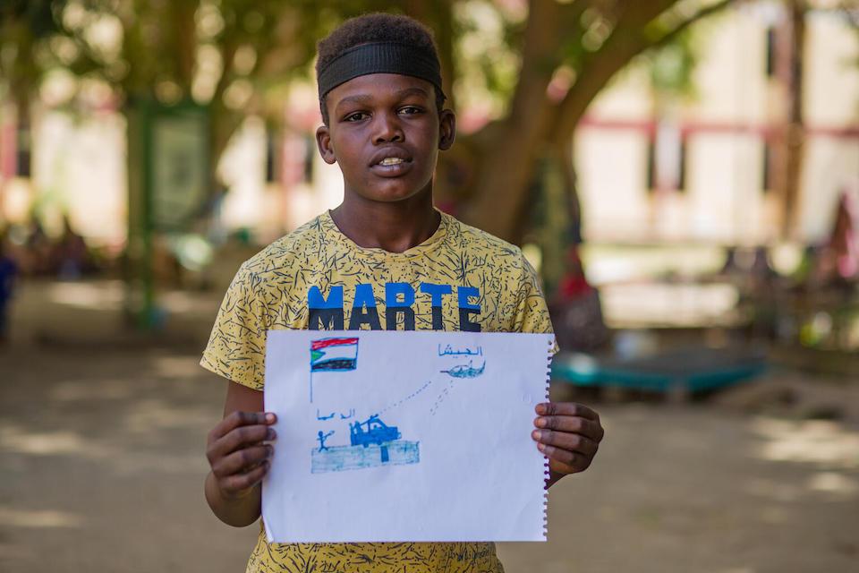 Ahmed displays his drawing during psychosocial activities at a UNICEF-supported gathering center in Madani, Sudan, for families displaced by conflict.
