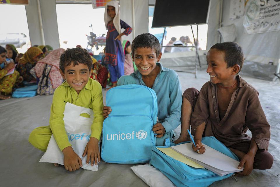 Students receive learning materials from UNICEF inside a temporary learning center established to help kids get back to learning after 2022 flooding destroyed their school.