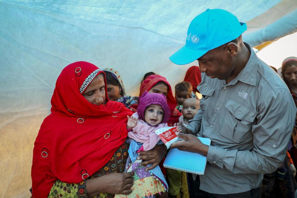 Zivai Murira, Regional Nutrition Advisor to the UNICEF South Asia Regional Office, hands a packet of Ready-to-Use Therapeutic Food (RUTF) to 1-year-old Hussain, who is suffering from severe acute malnutrition at a camp for displaced families in Sohbatpur district, Baluchistan province of Pakistan.