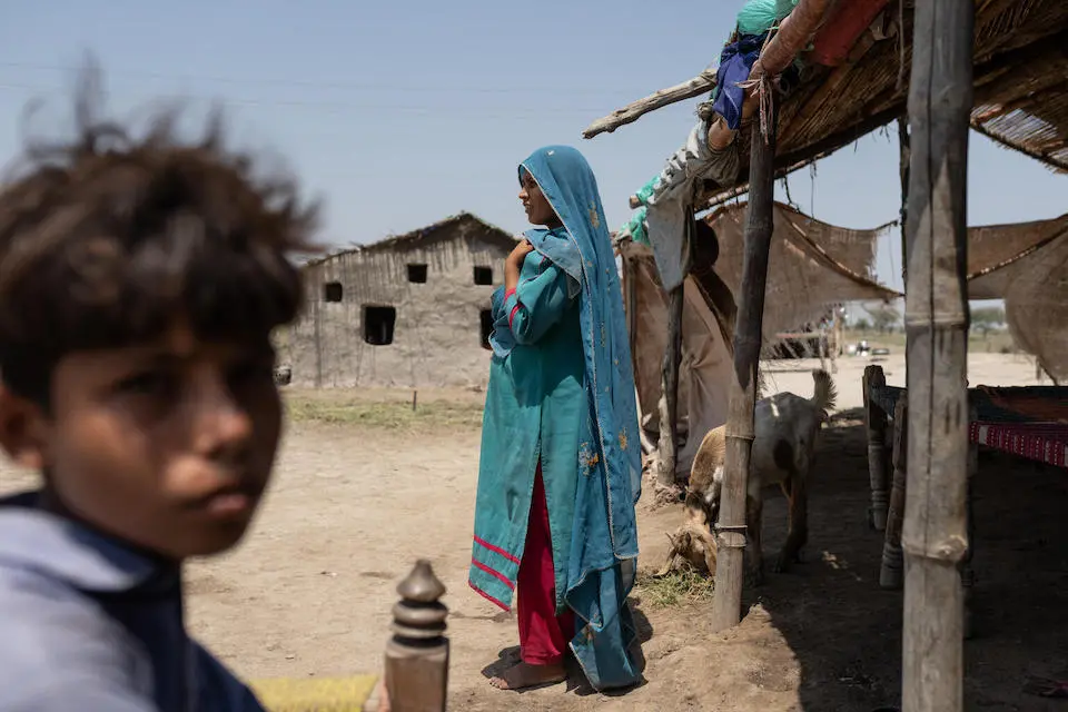 A mother stands in front of her improvised house in Moosa Jessear village, Sindh Province.