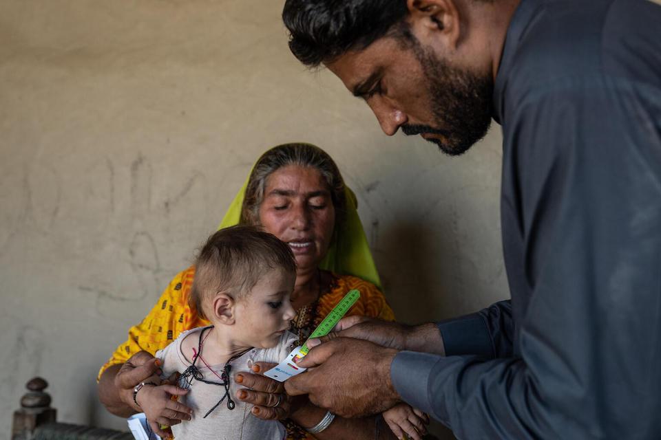 An eight-month-old baby is being measured by a health worker to detect severe malnutrition in Sindh Province.