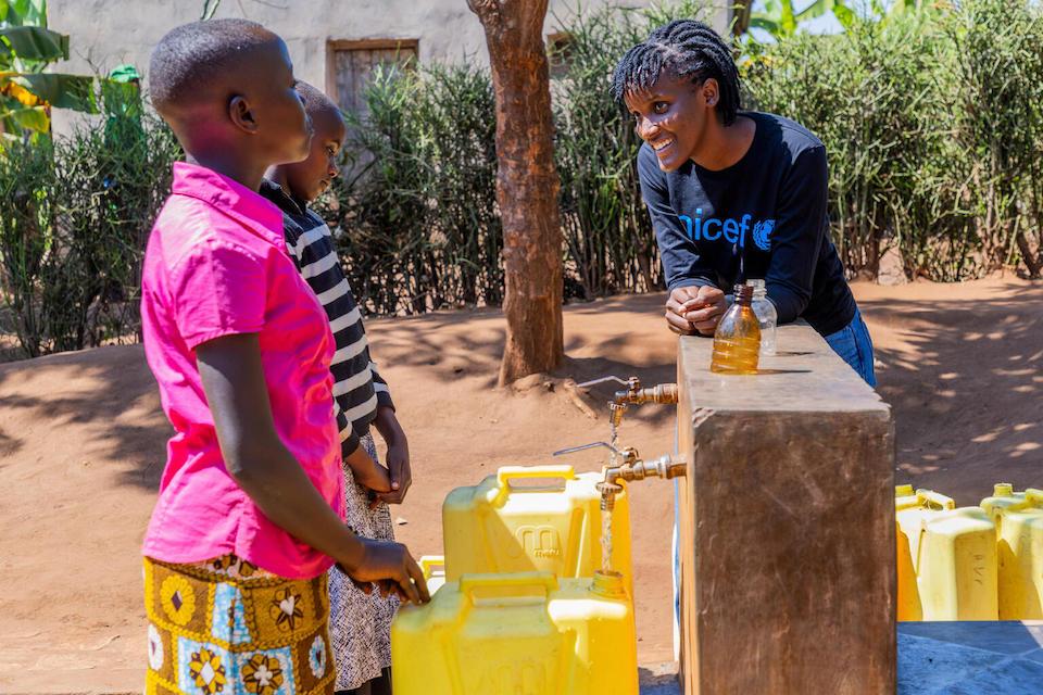 UNICEF Goodwill Ambassador Vanessa Nakate speaks with girls as they fill containers from taps that are part of a solar-powered water supply system in Kigarama Sector, Kirehe District, Eastern Province of Rwanda.