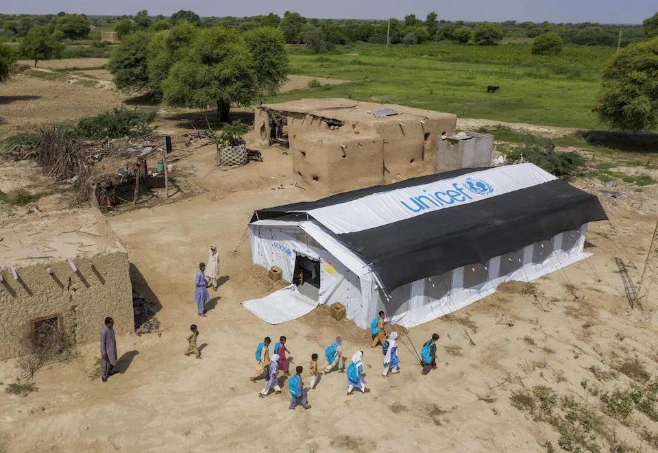 School children with UNICEF backpacks stand outside a UNICEF temporary learning center next to flooded areas of Lasbela, Baluchistan province, Pakistan.