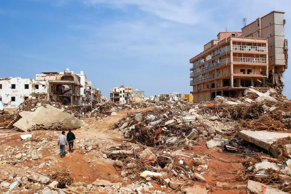 Men walk past debris of buildings caused by flash floods in Derna, eastern Libya, on Sept. 11, 2023.