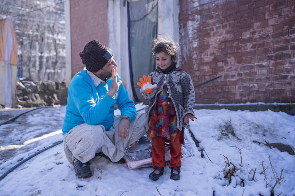 UNICEF Planning, Monitoring and Evaluation Officer Zaheer Ahmad interacts with 6-year-old Wajiha during the distribution of winter kits to flood-affected children in Sheringal, Upper Dir District, Khyber Pakhtunkhwa Province, Pakistan, on Feb. 1, 2023.