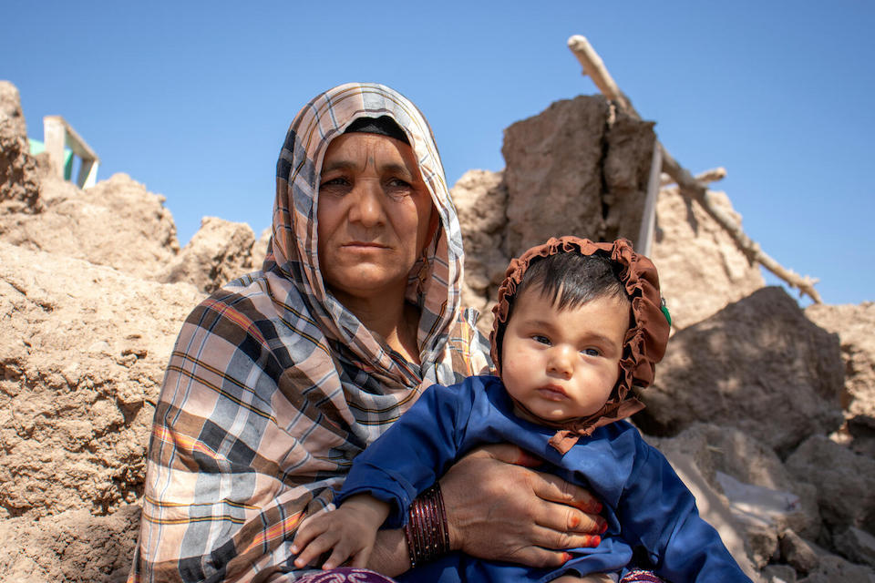 On Oct. 9, 2023, Ziba holds a 6-month-old boy amidst rubble in Zinda Jan district, Herat Province, Afghanistan.