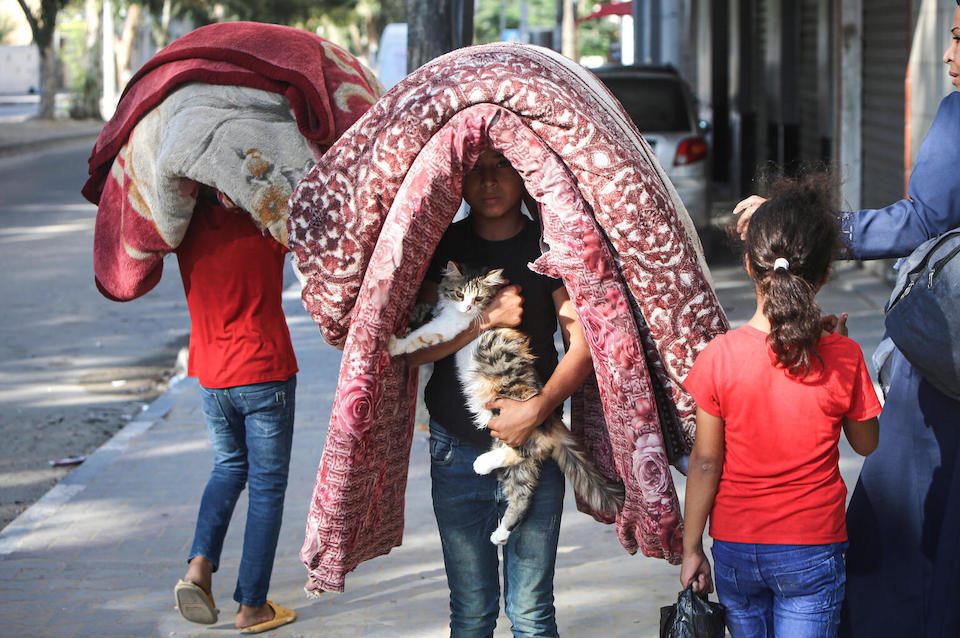 On Oct. 14, 2023, 7-year-old Salem carries mattresses on his head and his cat in his arms, leaving Tal Al-Hawa neighborhood in Gaza City with his family to seek shelter elsewhere in the Gaza Strip.