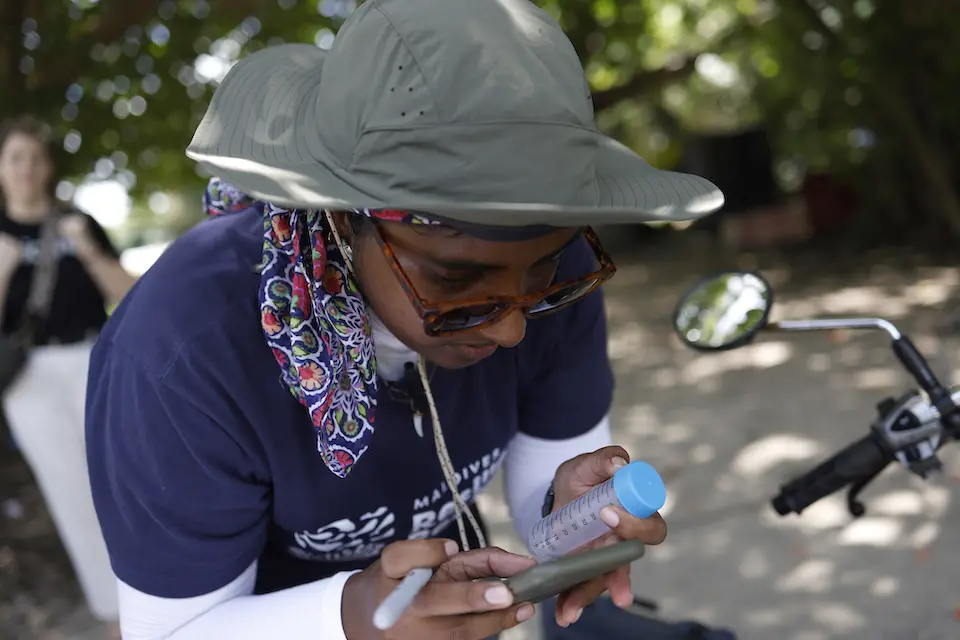 Muf, who is in her 20s, testing nitrogen levels in the water off the coast of Hithadhoo island, Laamu Atoll, Maldives.