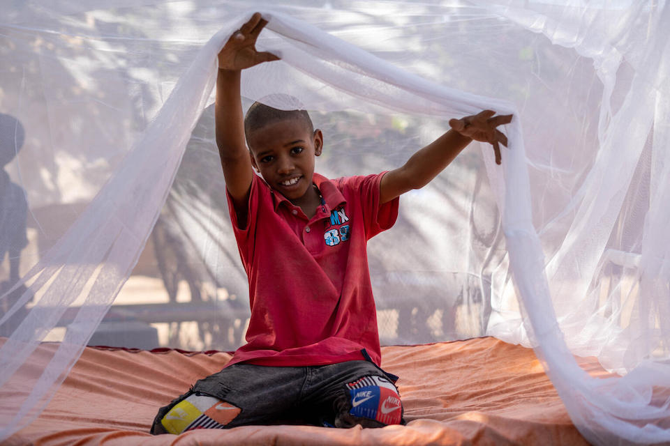 In Kassala State, Sudan, a young boy sits under a long-lasting insecticide-treated mosquito net, which helps prevent malaria.