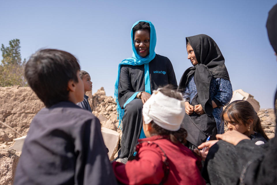 UNICEF Communication Officer Rebecca Phwitiko sits with children in their village in Afghanistan following one of several earthquakes that hit the area in Oct. 2023.