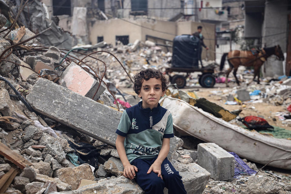 Mohammed, an 8-year-old from Rafah City, sits on the rubble of his family's house, bombed in an Israeli airstrike.
