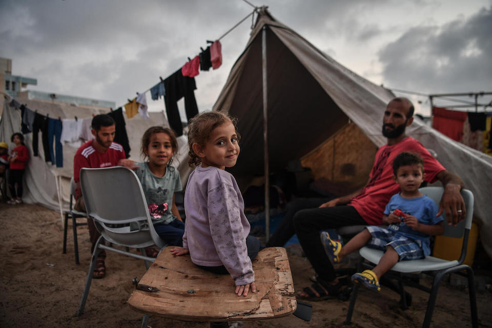 Four-year-old Lama and family members sit in front of their tent at UNRWA shelter camp in Khan Younis, southern Gaza Strip.