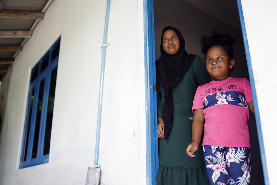 A mother and her daughter look out from the doorway of their home in Kunahandhoo, Laamu Atoll, the Maldives.