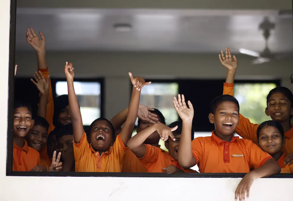 At UNICEF-supported Ihaddhoo School in Gan, Laamu Atoll, the Maldives, a group of students wave to visitors through an open classroom window.