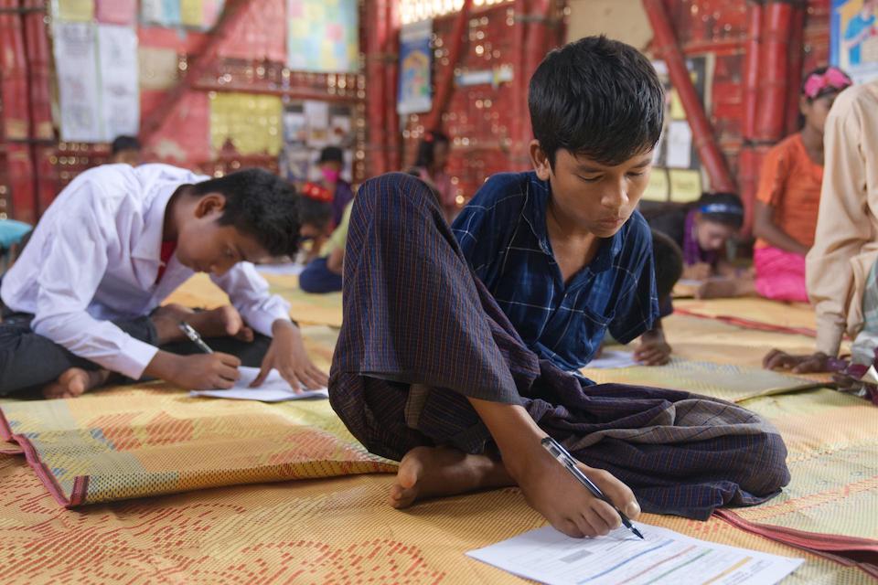 At school in Bangladesh, Ehsan, 14, a refugee from Myanmar who lost his arms in an accident, writes with his left foot, a skill he learned with support from UNICEF that enables him to continue his education..
