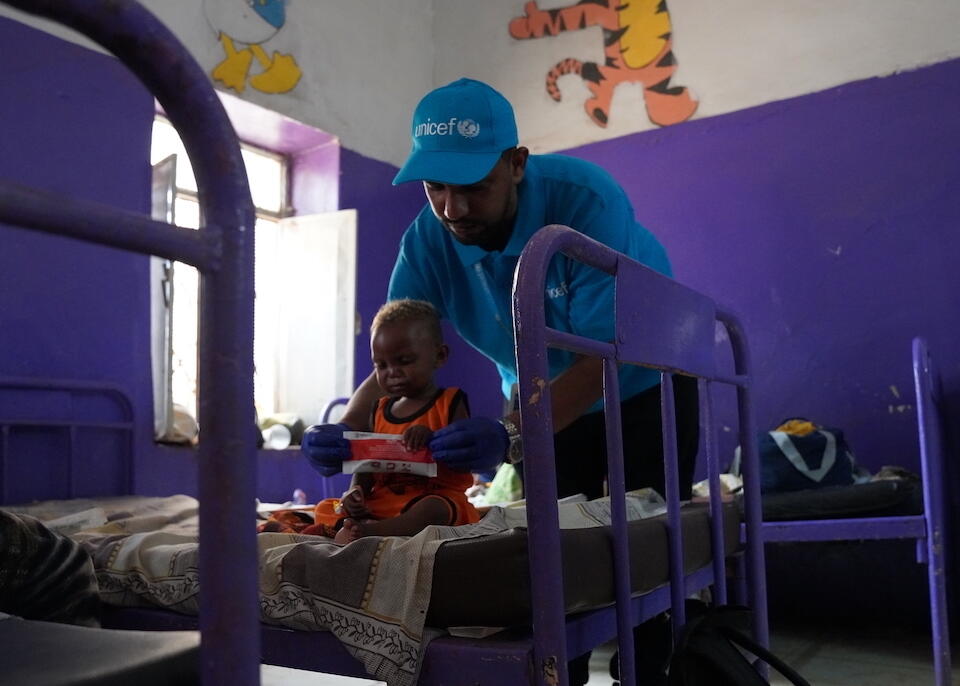 UNICEF Health and Nutrition Officer Mohamed Almugtba Khider feeds 16-month-old Mahdi with Ready-to-Use Therapeutic Food (RUTF) to help him recover from severe acute malnutrition at UNICEF-supported children's hospital in Wad Madani, where thousands of people have fled to escape the Sudan conflict.