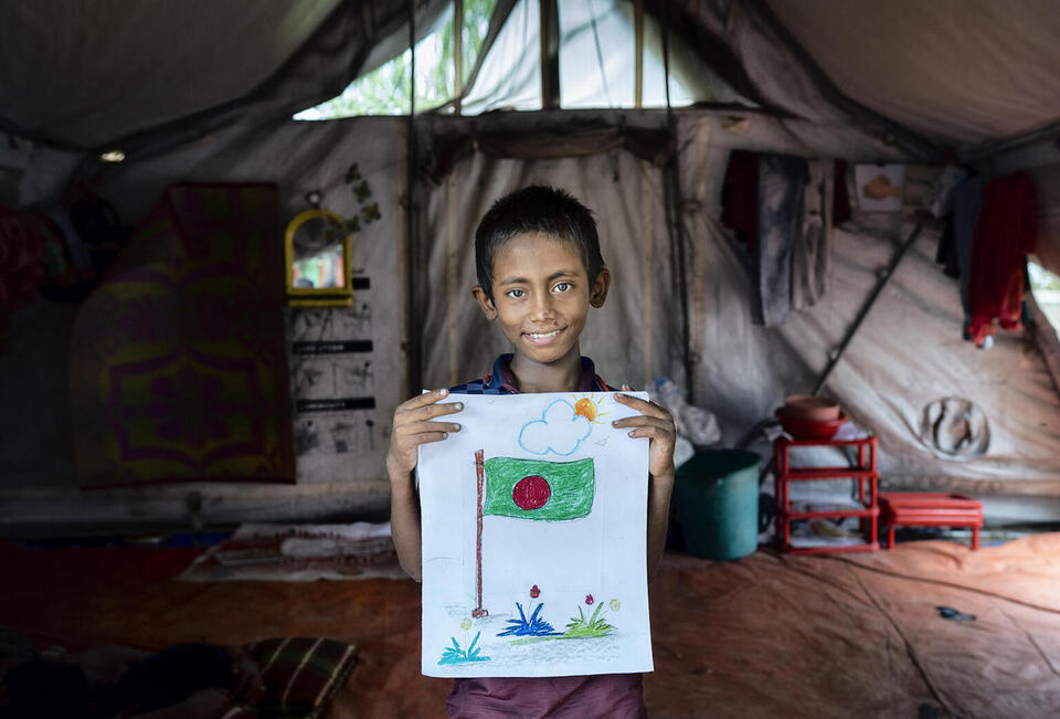 Hasan, 10, holds a drawing he made while participating in a support session at UNICEF's child protection hub in Gabtoli, Dhaka, Bangladesh.