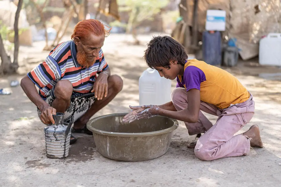 A boy and his father use a hygiene kit provided by UNICEF to wash their hands at the Al-Alili camp in Al Khawkhah district, Al-Hudaydah, Yemen.