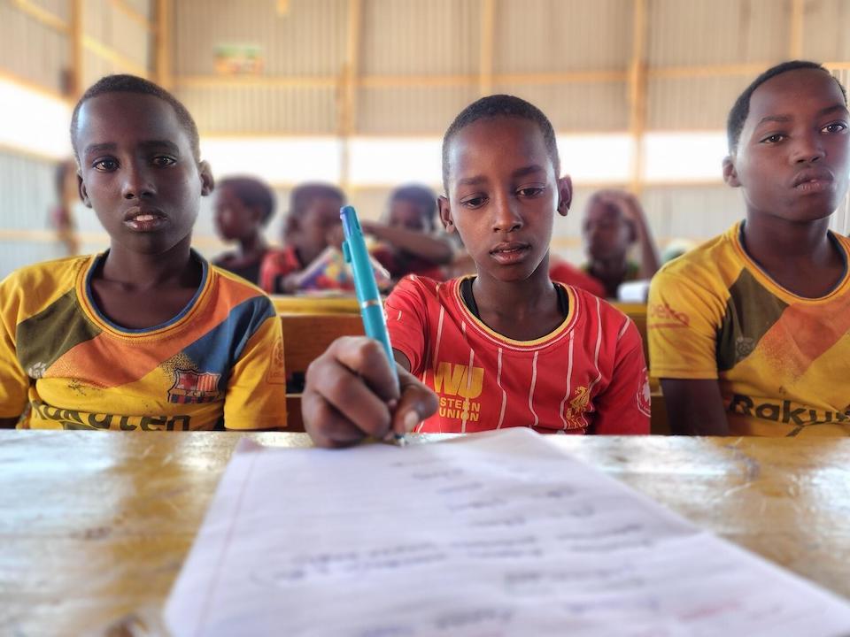 Three students sit at a desk at a temporary school UNICEF set up for displaced children staying at Deebwin camp in Baidoa, Somalia.