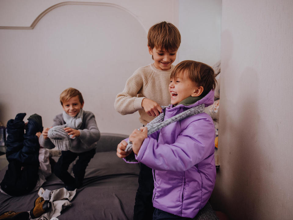 In Odesa, Ukraine, siblings try on new sets of warm winter clothes received from UNICEF.
