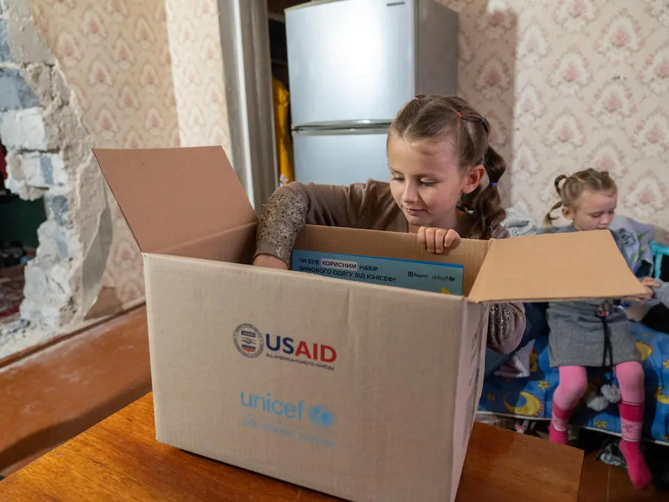 On Oct. 29, 2023, in Izium, Kharkivska oblast, Ukraine, Vika, 8, examines a winter clothes kit received from UNICEF.