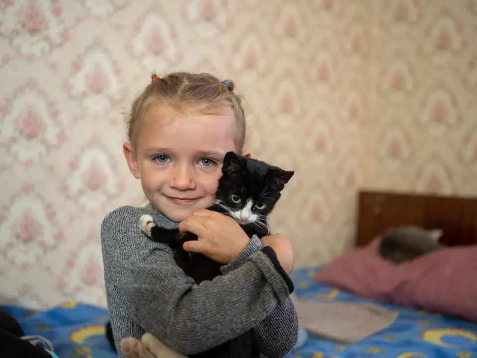 In Izium, Kharkivska oblast, Ukraine, Maria, 4, holds a cat in the house where her family is living.