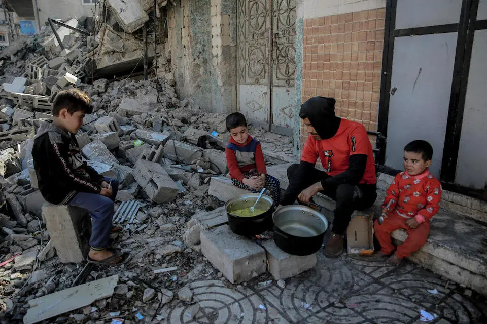 Khaled, 35, cooks food for his children over a wood fire due to gas shortages, in front of their destroyed home in al-Rimal neighborhood, west of Gaza City.