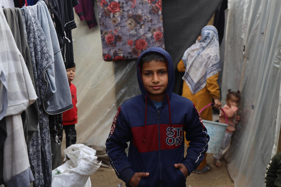 On Jan. 11, 2024, 13-year-old Abedalrahman stands beside tents at a shelter center located on the grounds of Al-Aqsa University in the Gaza Strip.