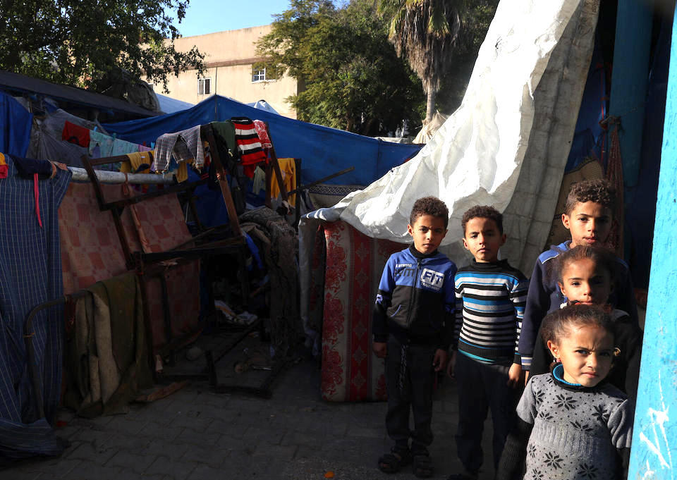 Children stand outside the tent where they are living in a shelter for internally displaced persons in Rafah, southern Gaza Strip.