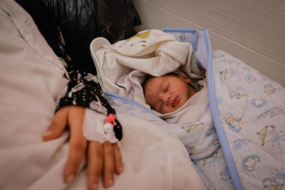 On Jan. 12, 2024, a newborn baby sleeps beside her mother in the Emirati maternity hospital in Rafah, southern Gaza Strip.