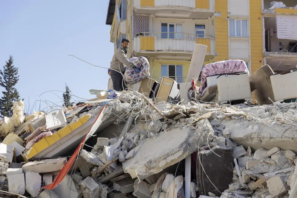 Two earthquake survivors look for blankets in the rubble of a collapsed building after two earthquakes hit Gaziantep, Türkiye on Feb. 6, 2023..