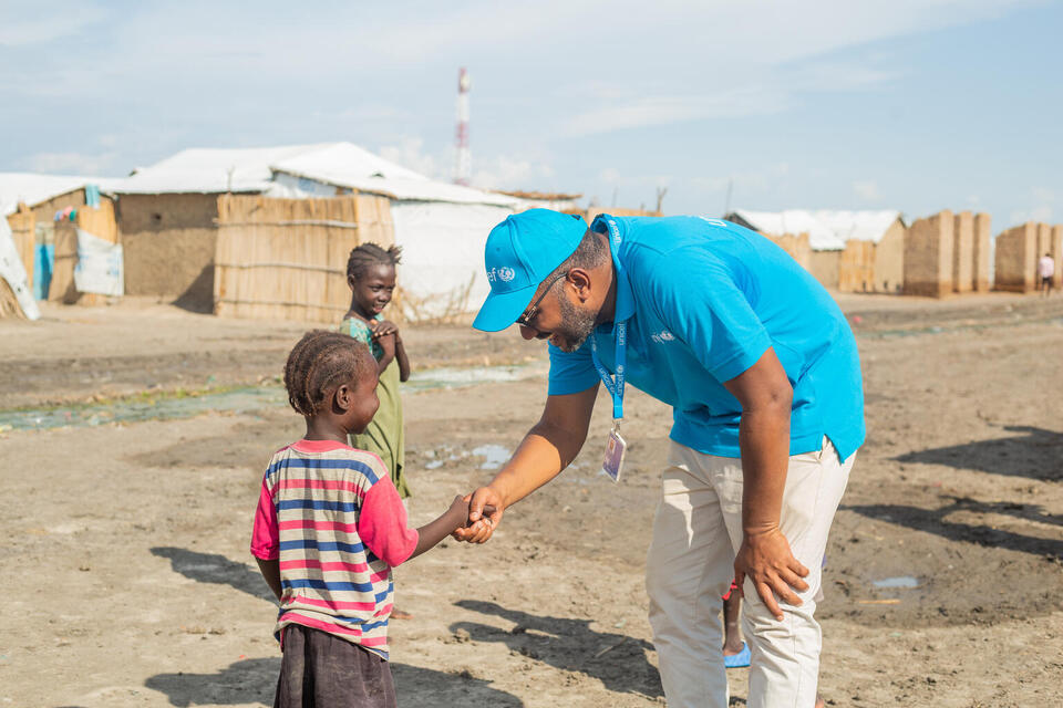 A UNICEF staff member shakes the hand of a young child at a refugee camp in White Nile State, Sudan, during the Accelerated Child Survival campaign supported by UNICEF. 