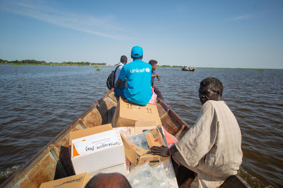 A UNICEF staff member and local partners travel by boat to deliver vital health supplies and vaccines to a hard-to-reach location in White Nile State, Sudan.