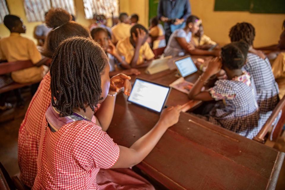 Children in Guinea participate in a classroom lesson with the help of tablets.