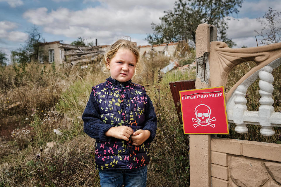 In Chistovodivka, a village in the Kharkiv region of Ukraine, 4-year-old Veronika stands near a sign that reads "Danger of Mines."