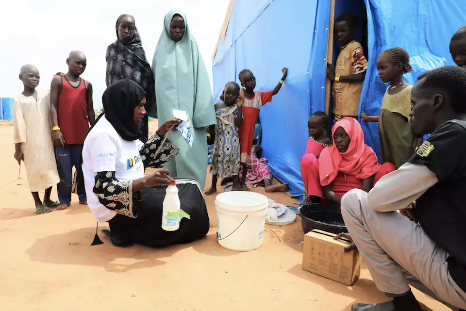 Mouwahib, in white shirt, conducts a UNICEF-supported water treatment awareness demonstration in southeastern Chad.