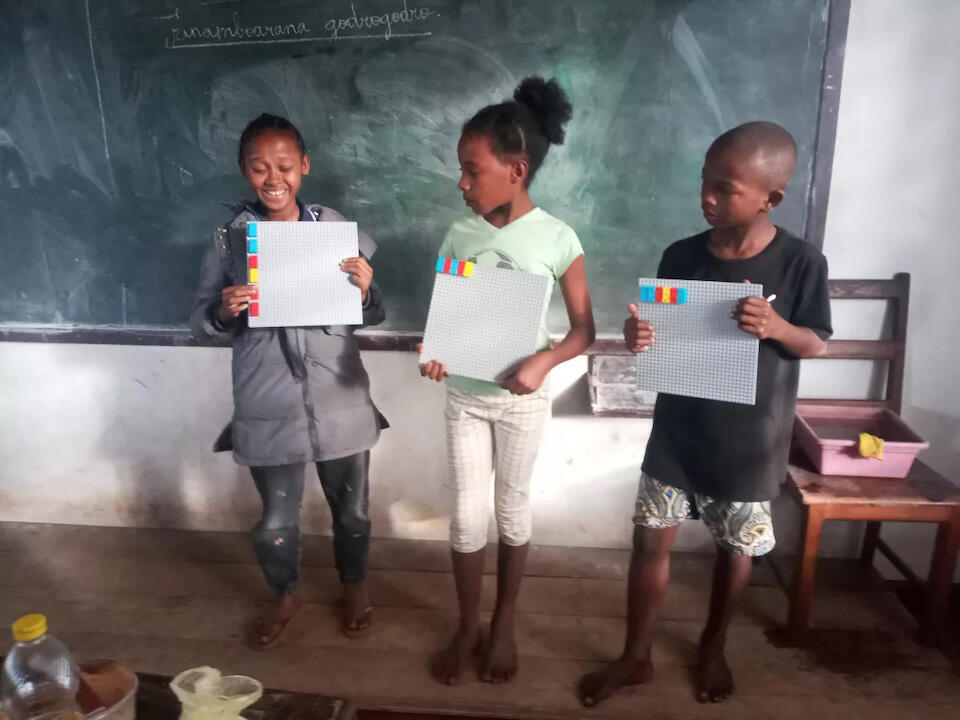 Three blind students hold up their Braille Lego bricks, a tool being used in an inclusive classroom at a UNICEF-supported school in east Madagascar.