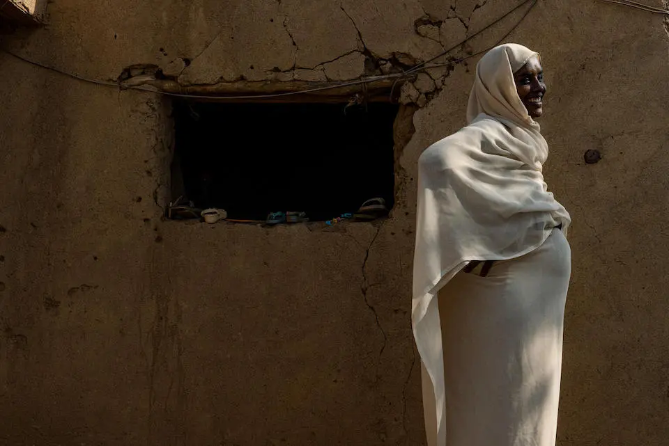In Aroma town, Kassala state, Sudan, mother Aisha Alamin Ali, 29, who is seven months pregnant, stands in front of her family’s home.