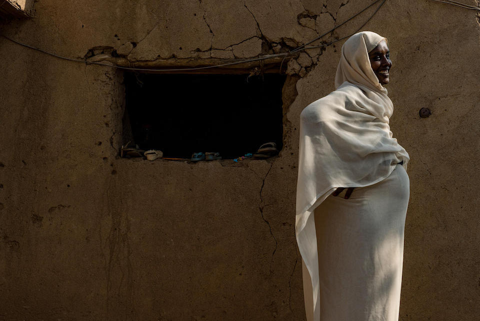 In Aroma town, Kassala state, Sudan, mother Aisha Alamin Ali, 29, who is seven months pregnant, stands in front of her family’s home.