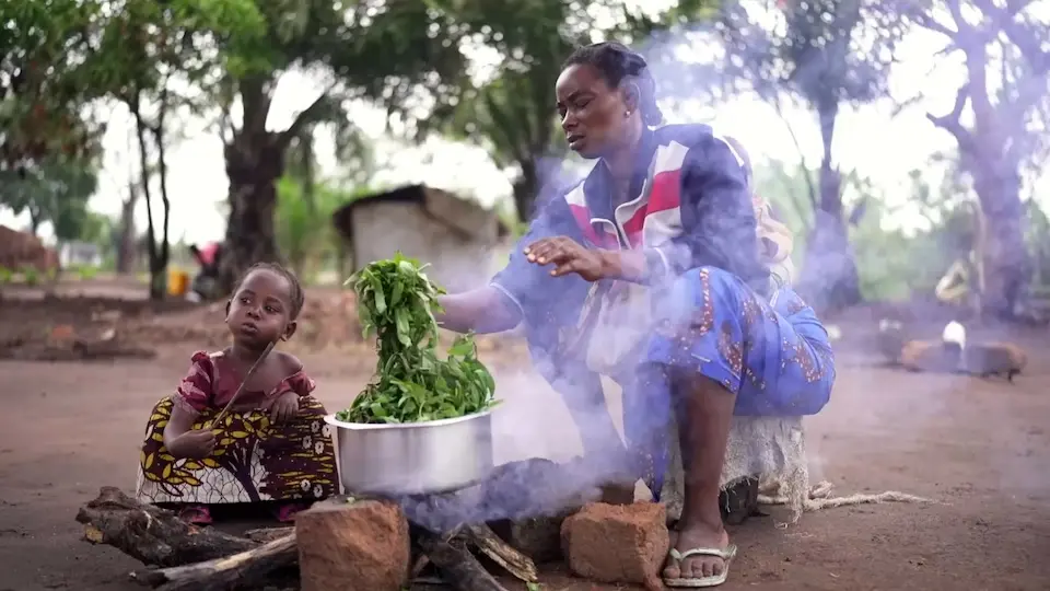Luzinga Mwayuma Moza and her child cook vegetables over a fire in Katamba village, Tanganyika province, eastern DRC.