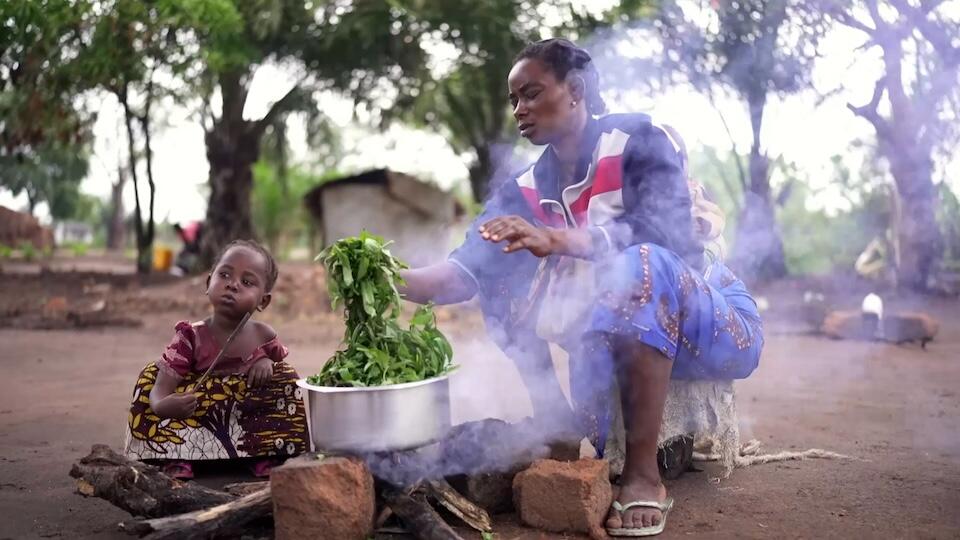 Luzinga Mwayuma Moza and her child cook vegetables over a fire in Katamba village, Tanganyika province, eastern DRC.