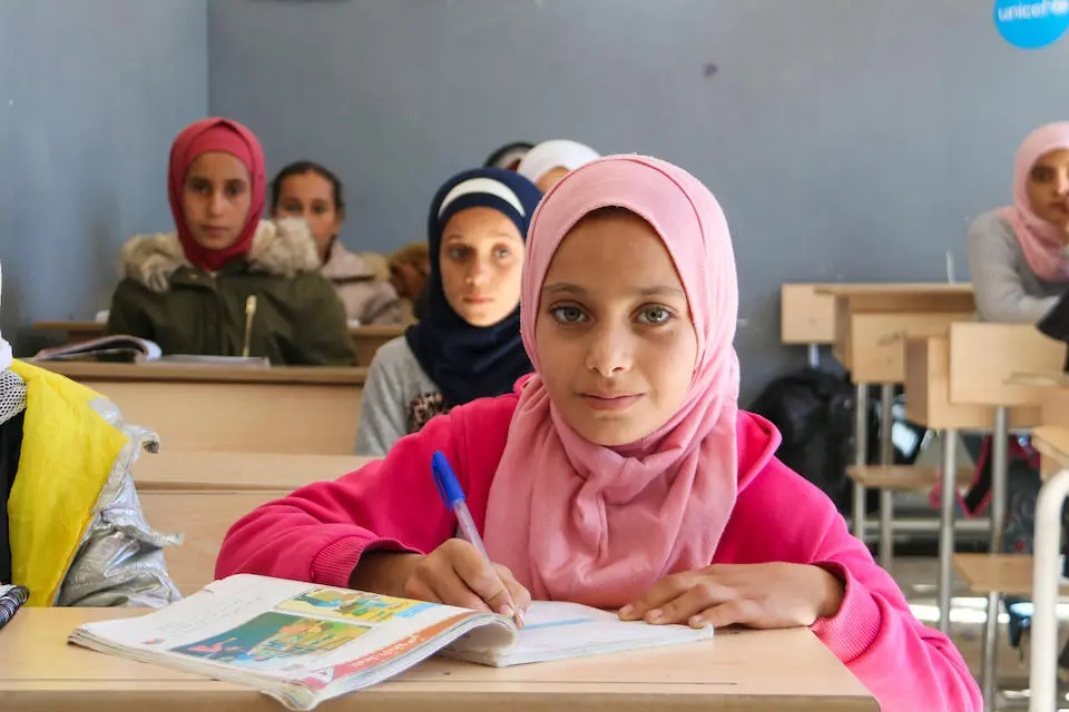 Sally, 11, Grade 6, writes at her desk during a lesson at the UNICEF-rehabilitated Al Tabni school, in Deir ez-zor governorate, Syria.