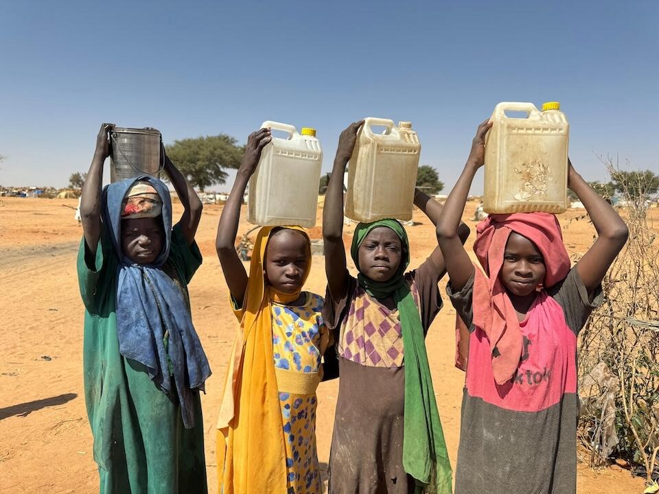 On Feb. 3, 2024, children carry containers of water after filling them at a UNICEF borehole inside Adré refugee settlement in Chad.