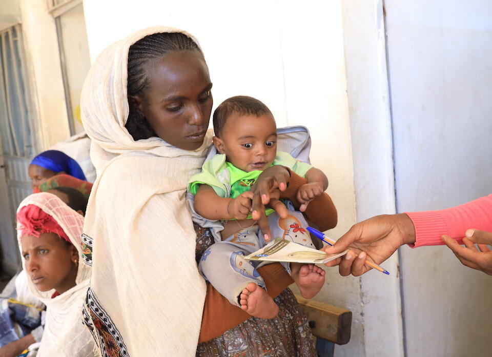 A mother holds her baby at a UNICEF-supported health facility in Tigray, Ethiopia, here the family is receiving services