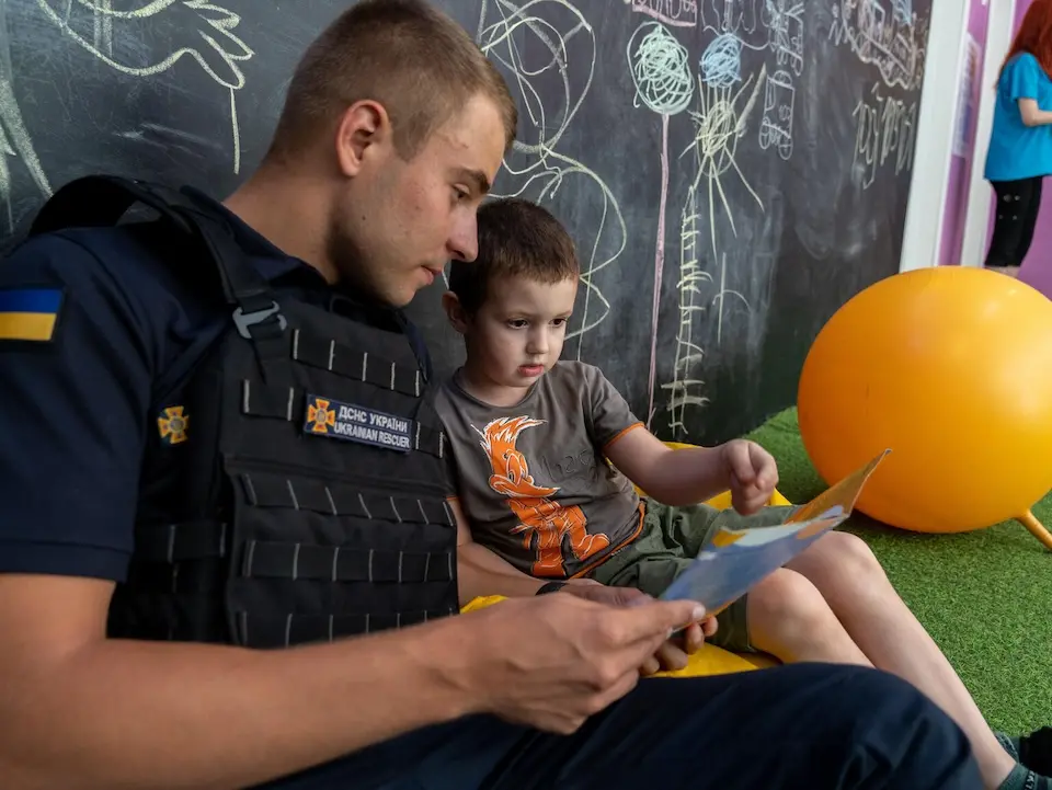 Dima, 4, reads a book about mine safety with a trained educator at a UNICEF Spilno Child Spot in Kherson, Ukraine.UNICEF