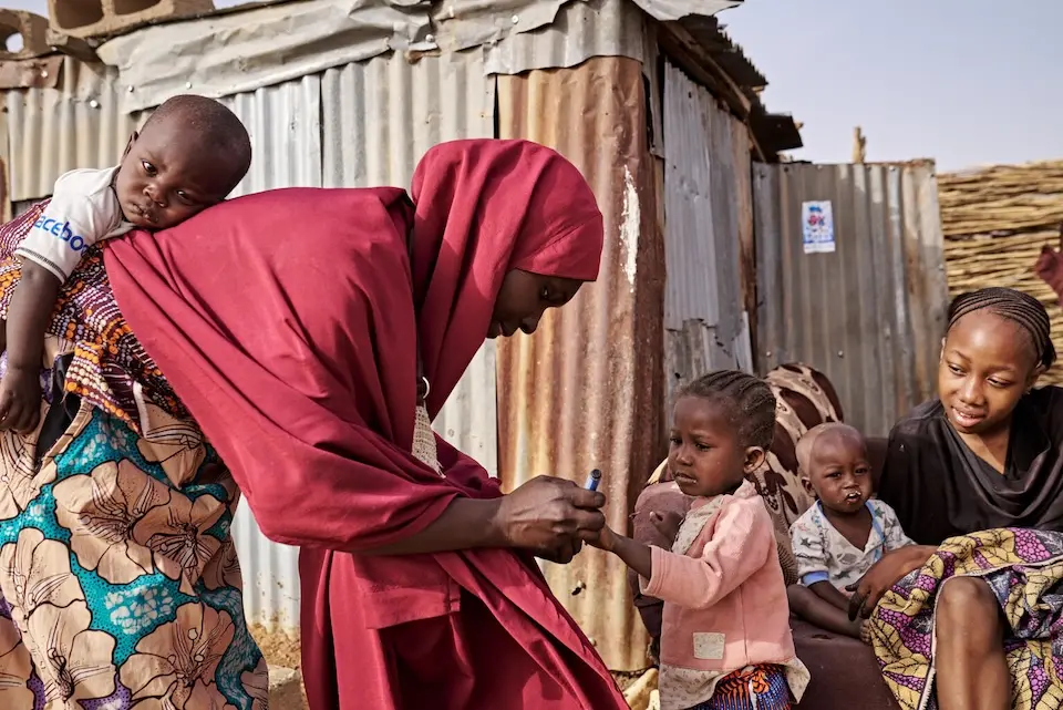 On Feb. 29, 2024, polio vaccinator Hafsat Mikauli 30, marks a girl’s finger with a whiteboard marker to indicate she has received the polio vaccine in Makurdi Gagi, Sokoto South LGA, Sokoto Sate, Nigeria.